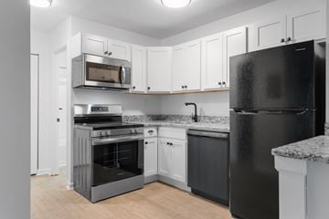 Medina apartment for rent - A black refrigerator stands in a kitchen with white cabinets and a black stove.