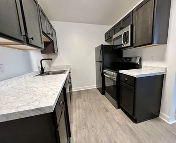 Northfield apartment for rent - an empty kitchen with black appliances and marble counter tops