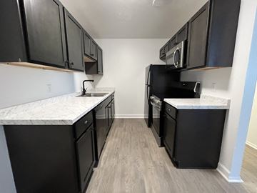 Northfield apartment for rent - an empty kitchen with black appliances and white marble counter tops