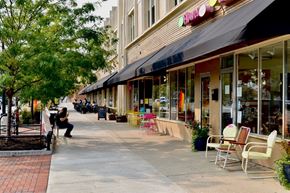 Lakewood apartment for rent - a city street with tables and chairs outside a store