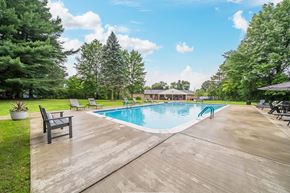 Mayfield Heights apartment for rent - A large outdoor swimming pool surrounded by trees and a wooden deck.