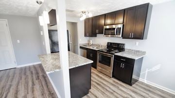 Berea apartment for rent - A kitchen with black cabinets and a granite countertop.