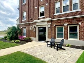 Lakewood apartment for rent - Two black chairs are on a patio in front of a brick building.