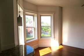 Cleveland apartment for rent - A sunny room with a large window and a view of a red building outside.