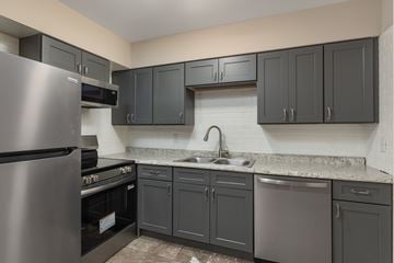 Chattanooga apartment for rent - A kitchen with a stainless steel refrigerator and dark grey cabinets.