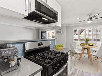 Blue tiled kitchen with stainless steel oven and microwave and view of hardwood floor dining room.
