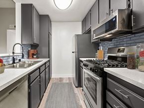 Reseda apartment for rent - Blue tiled kitchen with stainless steel microwave, oven, and refrigerator.