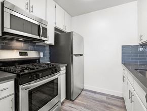 Sherman Oaks apartment for rent - Blue tiled kitchen with stainless steel oven, microwave, and fridge.