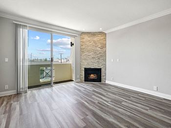 Hardwood floored living room with stone walled fireplace and balcony.