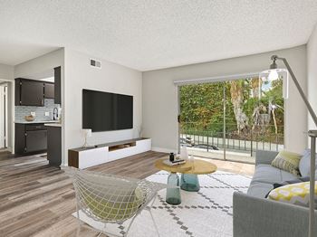 Hardwood floored living room with view of balcony and kitchen.