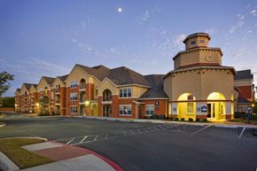 San Antonio apartment for rent - A large building with a tower and a parking lot in front.