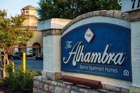 San Antonio apartment for rent - A sign for The Alhambra Senior Apartment Homes is displayed in front of a building.