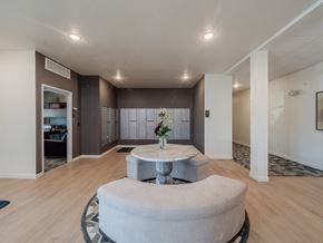Gillette apartment for rent - A round grey ottoman sits in the middle of a spacious room with a white table in front of it.