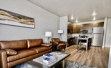 Hastings apartment for rent - A living room with a brown leather couch and a painting on the wall.