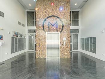 The lobby of a building with an elevator and a mosaic wall