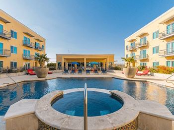 A swimming pool with a fountain in front of an apartment building