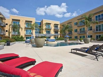 An apartment building with a pool and red chairs