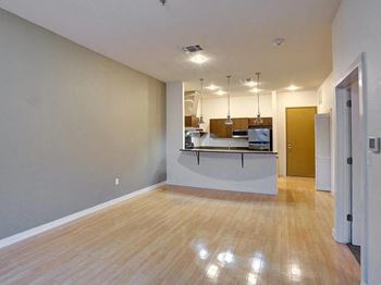 An empty living room and kitchen with a wood floor