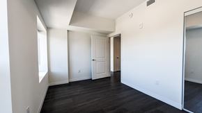 Kitchener apartment for rent - A spacious room with white walls and dark wood flooring.
