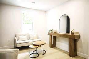 Kitchener apartment for rent - A living room with a white couch, a wooden table, and a round chair.