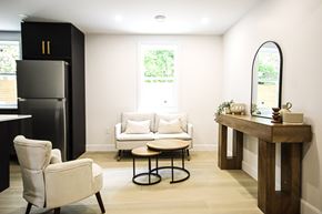 Kitchener apartment for rent - A black refrigerator stands next to a white chair in a room with a round table and a mirror.