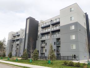 Waterloo apartment for rent - A large grey apartment building with balconies and trees in front.