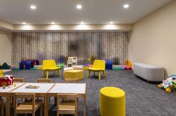 Jersey City apartment for rent - A room with a grey carpet and a grey sofa with a child's play area with a table and chairs.
