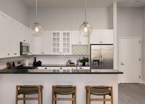Jersey City apartment for rent - Kitchen with white cabinetry, a wine rack, and black stone countertops with peninsula