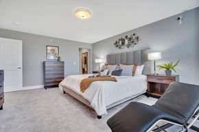 Ewing apartment for rent - Interior photo of the Primary Bedroom suite in a typical apartment at Ewing Town Center showing a bed, several dressers, end table with lamp, a lounge chair. There is a doorway showing access to the primary bath