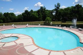 Belle Mead apartment for rent - Pike Run Village Pool photo showing the pool and several chairs and tables surrounded by a fence. There are several trees that highlight the landscape.