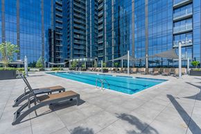 Secaucus apartment for rent - Exterior photo of the community’s pool located on the 5th floor at RVR showing a large pool surrounded by multiple shaded seating with patio chairs overlooking the community’s building.