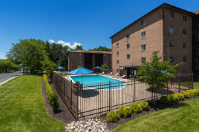 Wilmington apartment for rent - A pool surrounded by a black fence and green bushes.