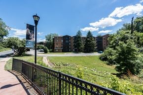 Wilmington apartment for rent - A black metal fence borders a grassy area with a building in the background.