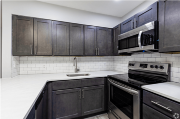 Newark apartment for rent - A kitchen with black cabinets and white countertops.