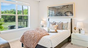 Grand Prairie apartment for rent - A bedroom with a large bed and a view of a fence and trees outside the window.