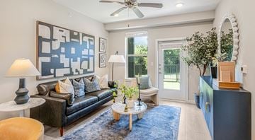Grand Prairie apartment for rent - A living room with a dark sofa and a blue rug.