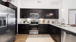 Justin apartment for rent - Gourmet apartment kitchen at Reatta Ranch in Justin, TX, featuring dark espresso cabinets, stainless steel appliances, and subway tile backsplash.