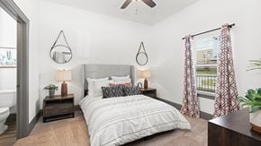 Justin apartment for rent - Model apartment bedroom at Reatta Ranch, with neutral decor, upholstered bed, and walk-in closet visible through the doorway.