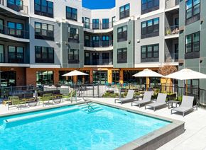 Rahway apartment for rent - a swimming pool in front of a building with chairs and umbrellas
