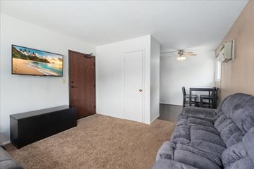 St. Paul Park apartment for rent - A living room with a grey couch and a flat screen TV mounted on the wall.