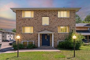 St. Paul Park apartment for rent - A brick house with a blue door and windows with curtains.