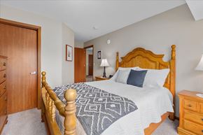 Mahtomedi apartment for rent - A bedroom with a large bed and a wooden dresser.