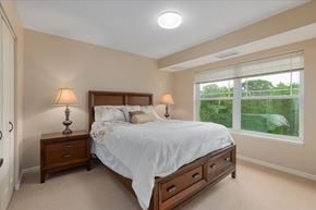 Forest Lake apartment for rent - A bedroom with a bed, nightstands, and a window overlooking a green landscape.