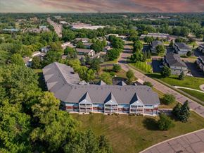 Woodbury apartment for rent - A large building with a grey roof is surrounded by trees and other buildings.
