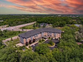 Woodbury apartment for rent - A large building surrounded by trees with a parking lot in front.