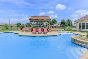 Texarkana apartment for rent - A pool with a gazebo and chairs around it.
