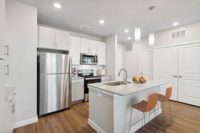 Katy apartment for rent - A modern kitchen with a stainless steel refrigerator, microwave, and wooden floors.