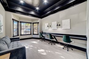 San Antonio apartment for rent - Coworking room with built-in counter, rolling chairs, and sofa seating under dark ceiling.