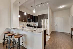 Farmers Branch apartment for rent - an open kitchen with bar stools and a stainless steel refrigerator