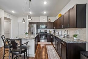 Garland apartment for rent - A kitchen with dark brown cabinets and a granite countertop.